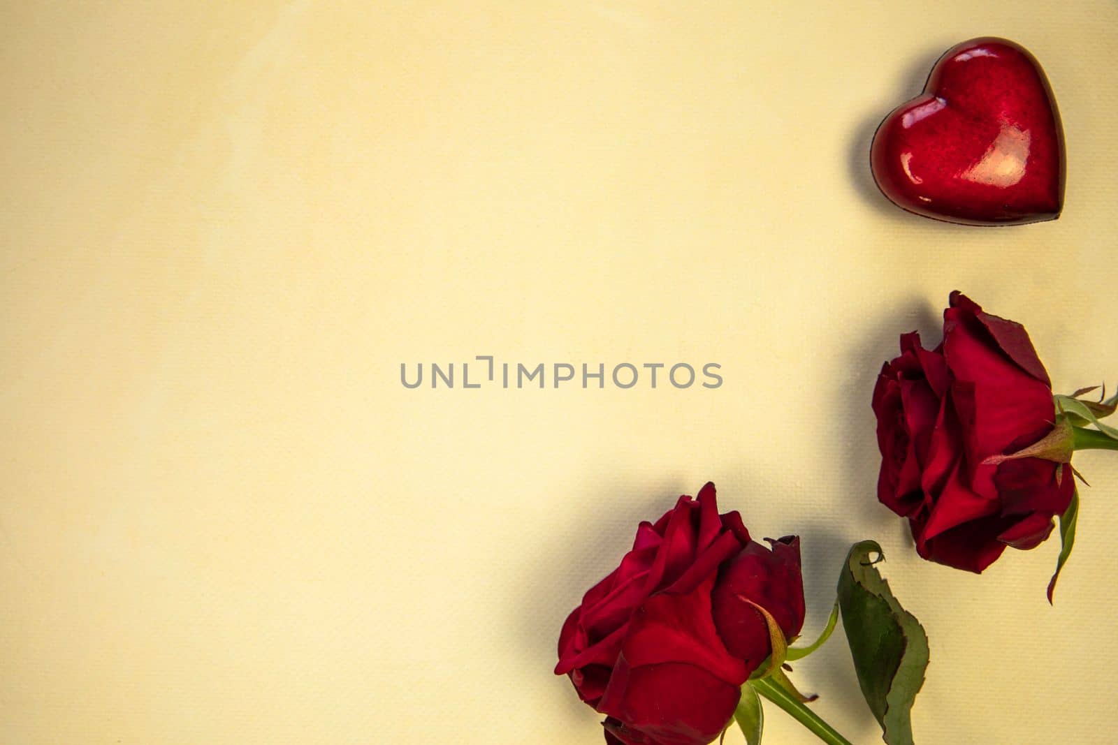 Flowers composition. Frame made of rose flowers and red heart on yellow background. Valentine's Day Mother's Day romantic background. Flat lay, top view, copy space.