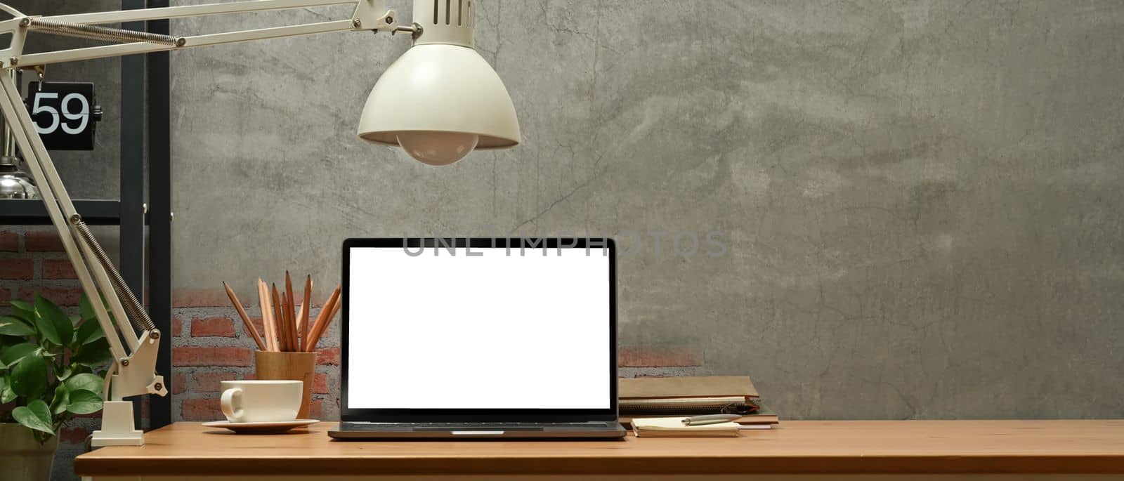 Stylish home office interior with laptop computer on wooden desk. Copy space, blank screen for graphic display montage by prathanchorruangsak