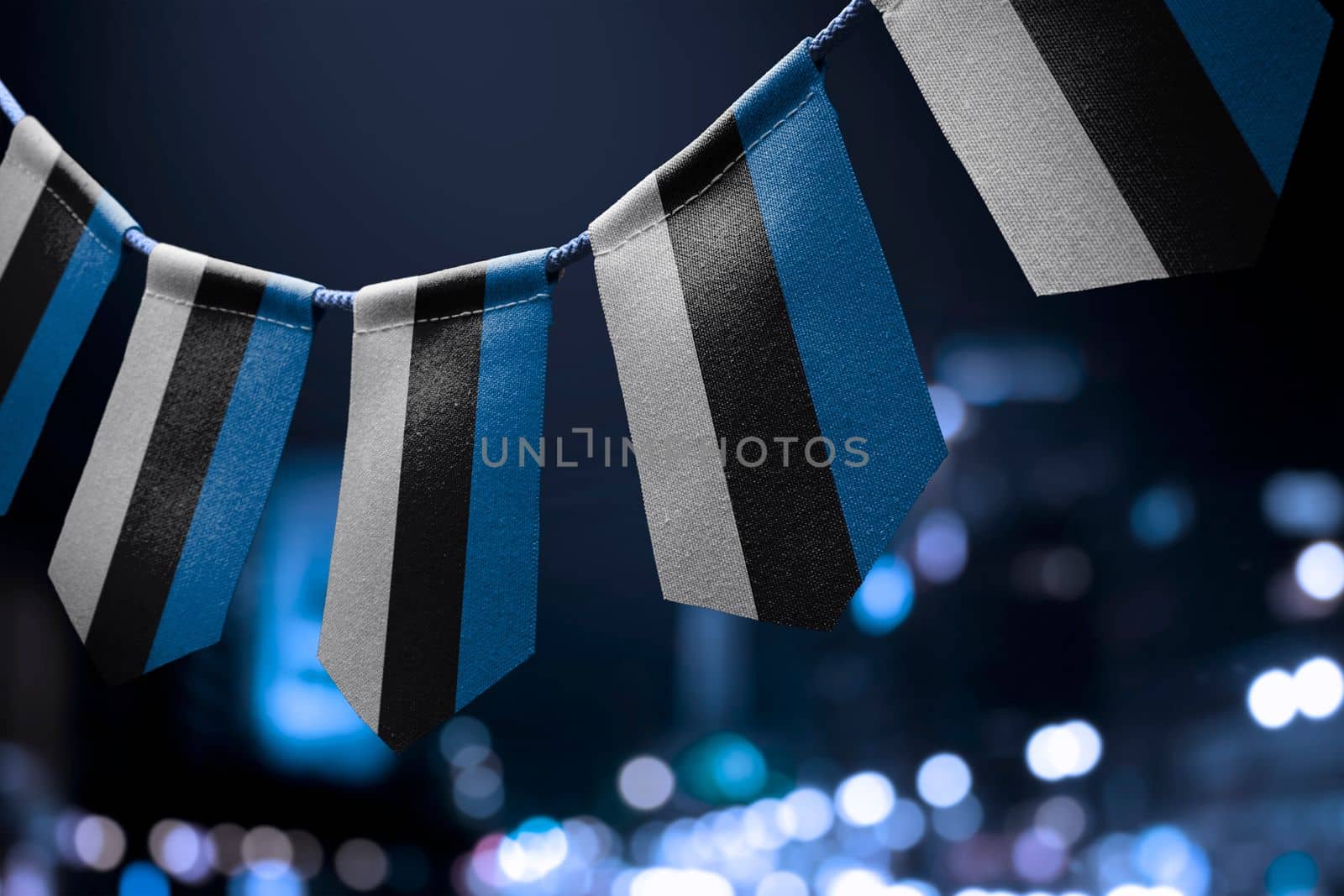 A garland of Estonia national flags on an abstract blurred background.