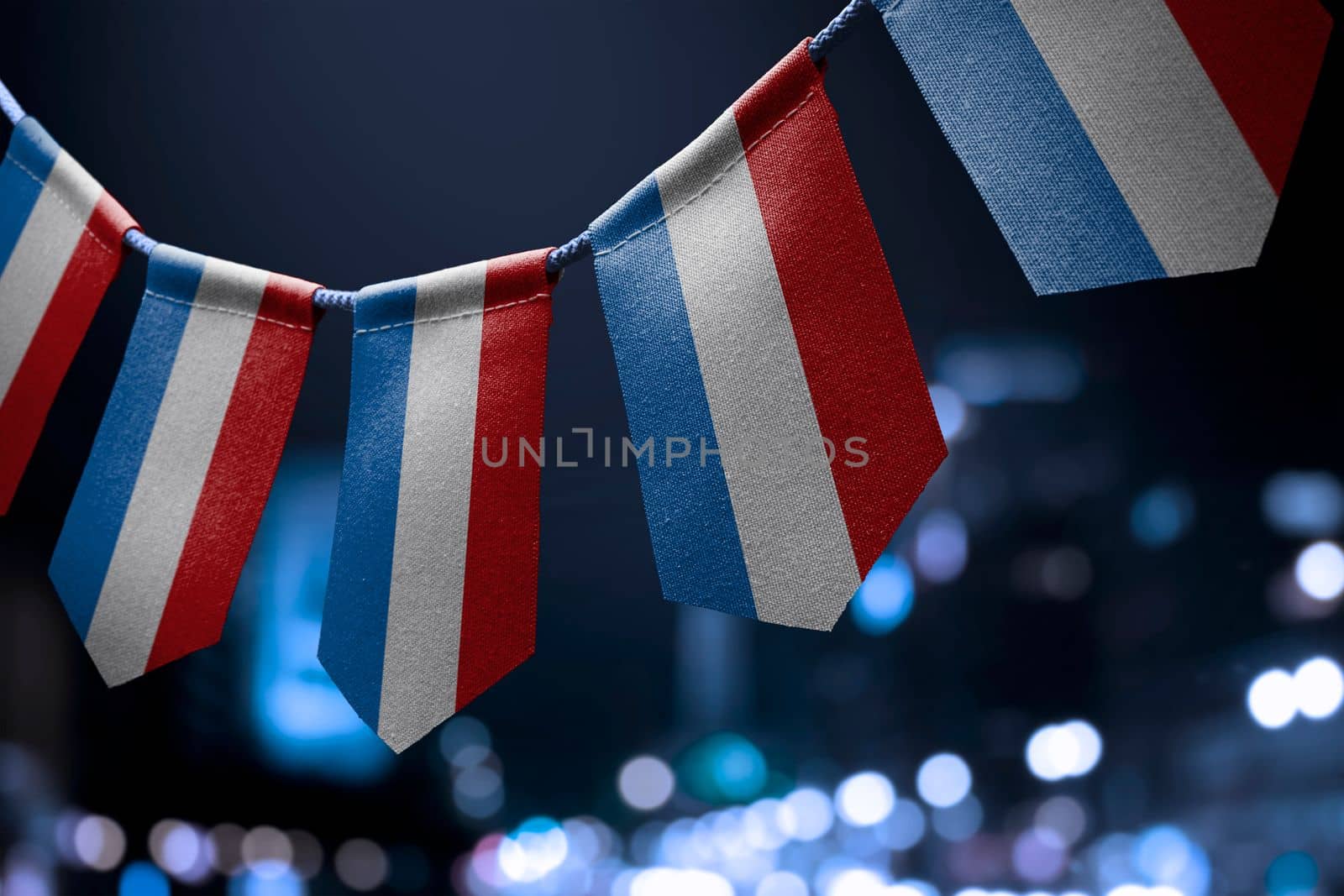 A garland of Netherlands national flags on an abstract blurred background by butenkow