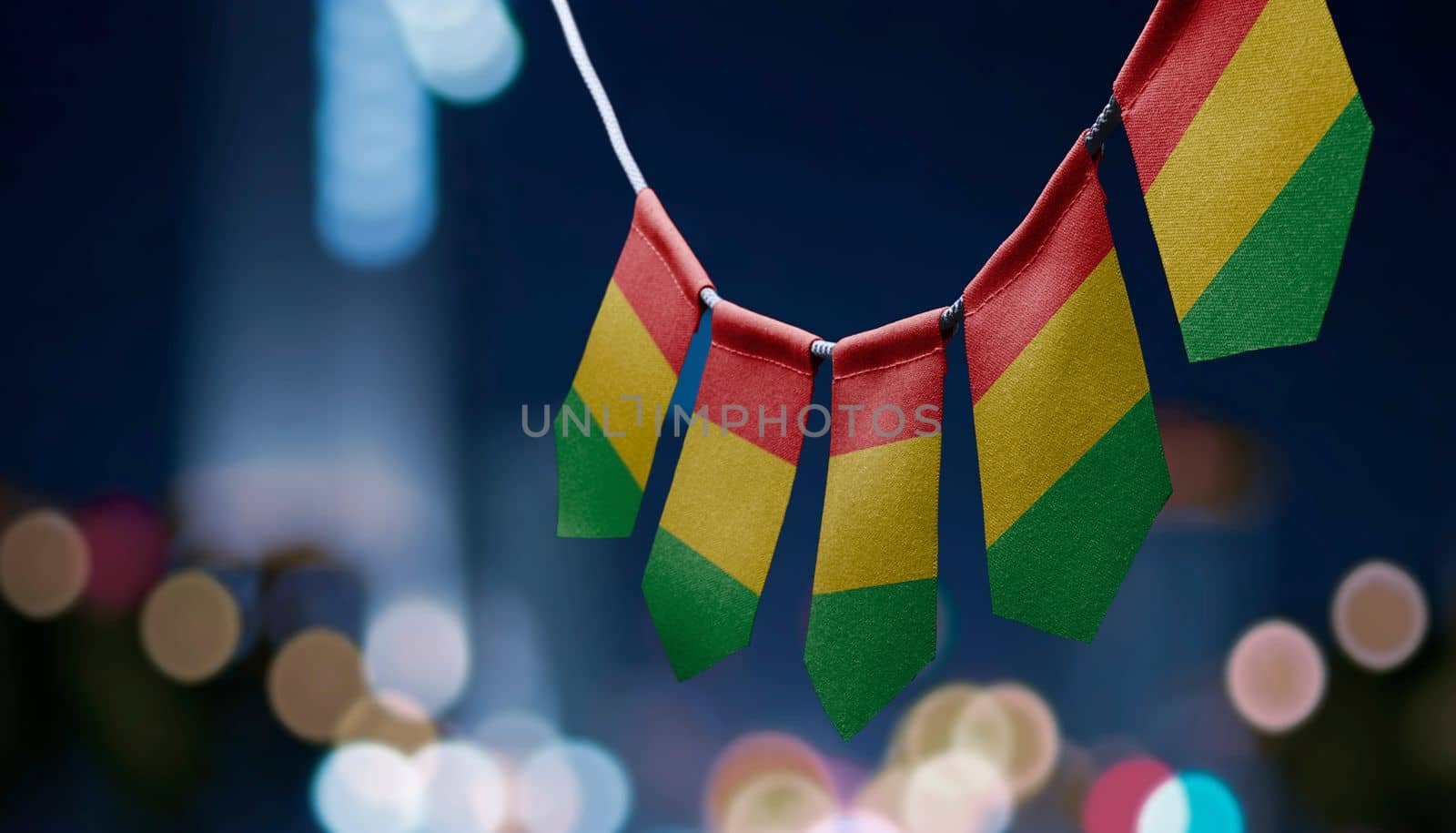 A garland of Guinea national flags on an abstract blurred background by butenkow