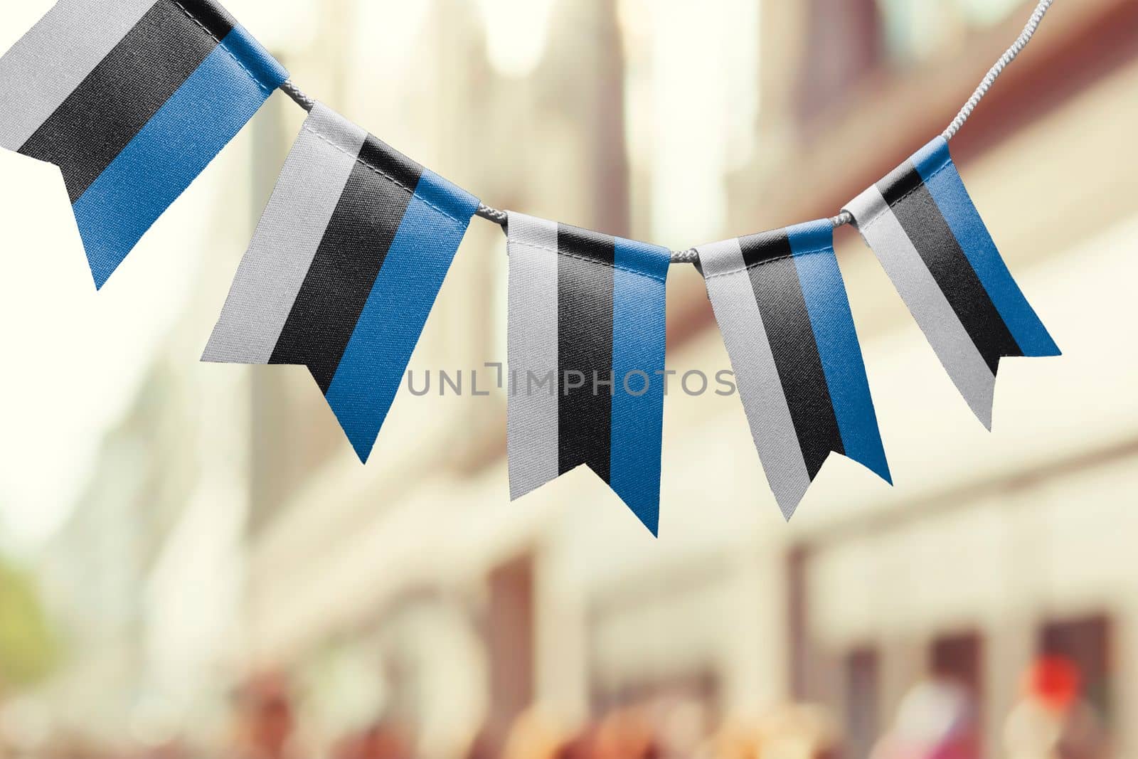 A garland of Estonia national flags on an abstract blurred background.