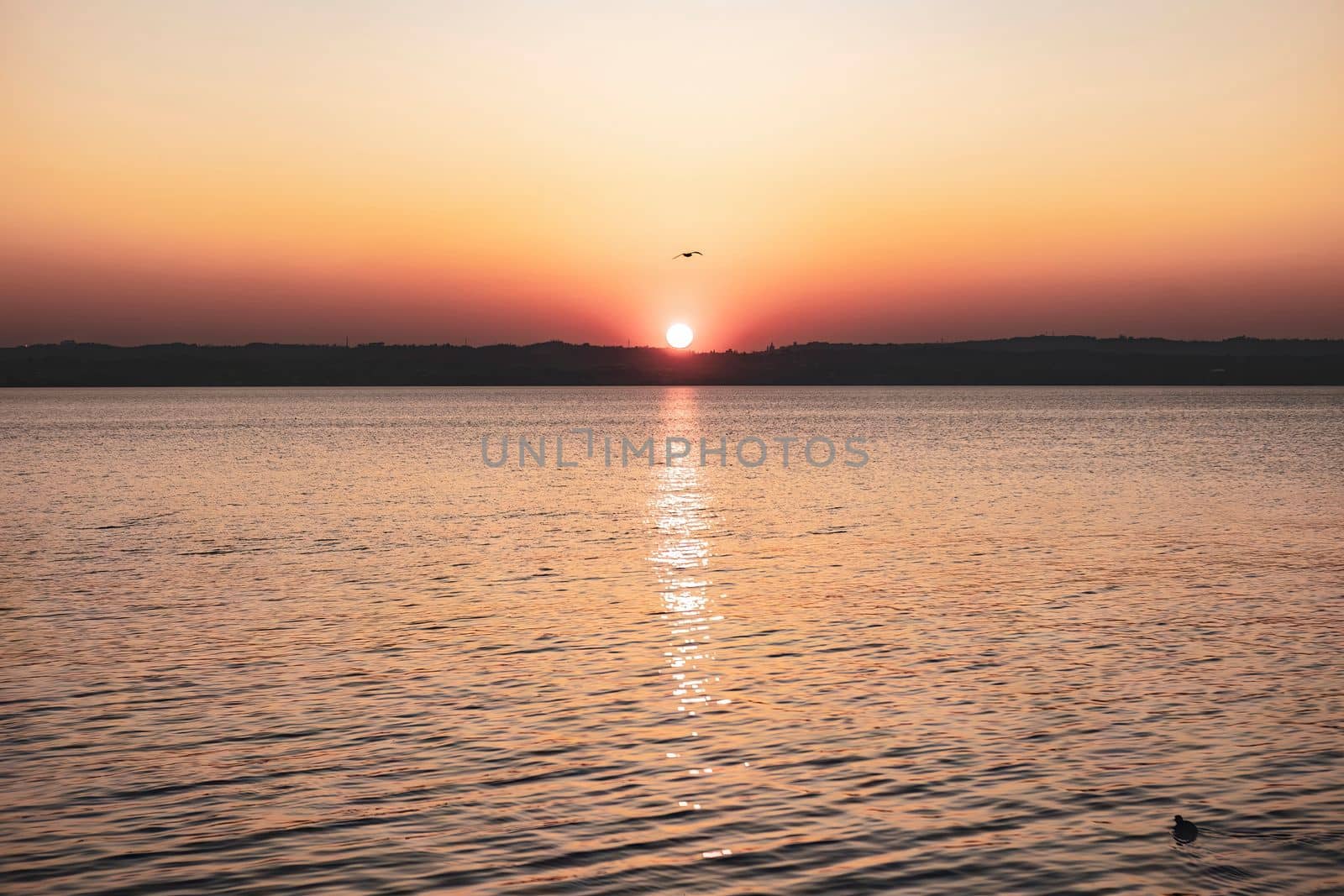 Beautiful sunset over the stunning Garda Lake in Italy, with the sun reflecting on the calm water and creating a peaceful atmosphere. Perfect for travel and nature-related projects.