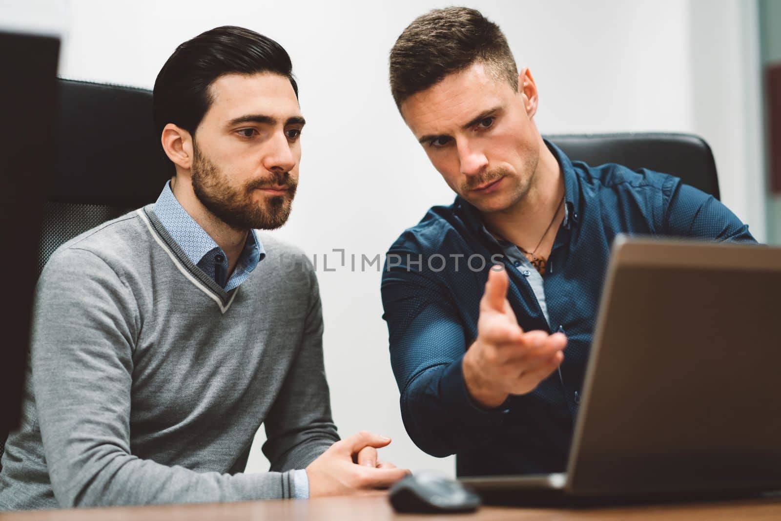 Couple of colleagues at a start up company working on laptop discussing an issue that needs to be solved by VisualProductions