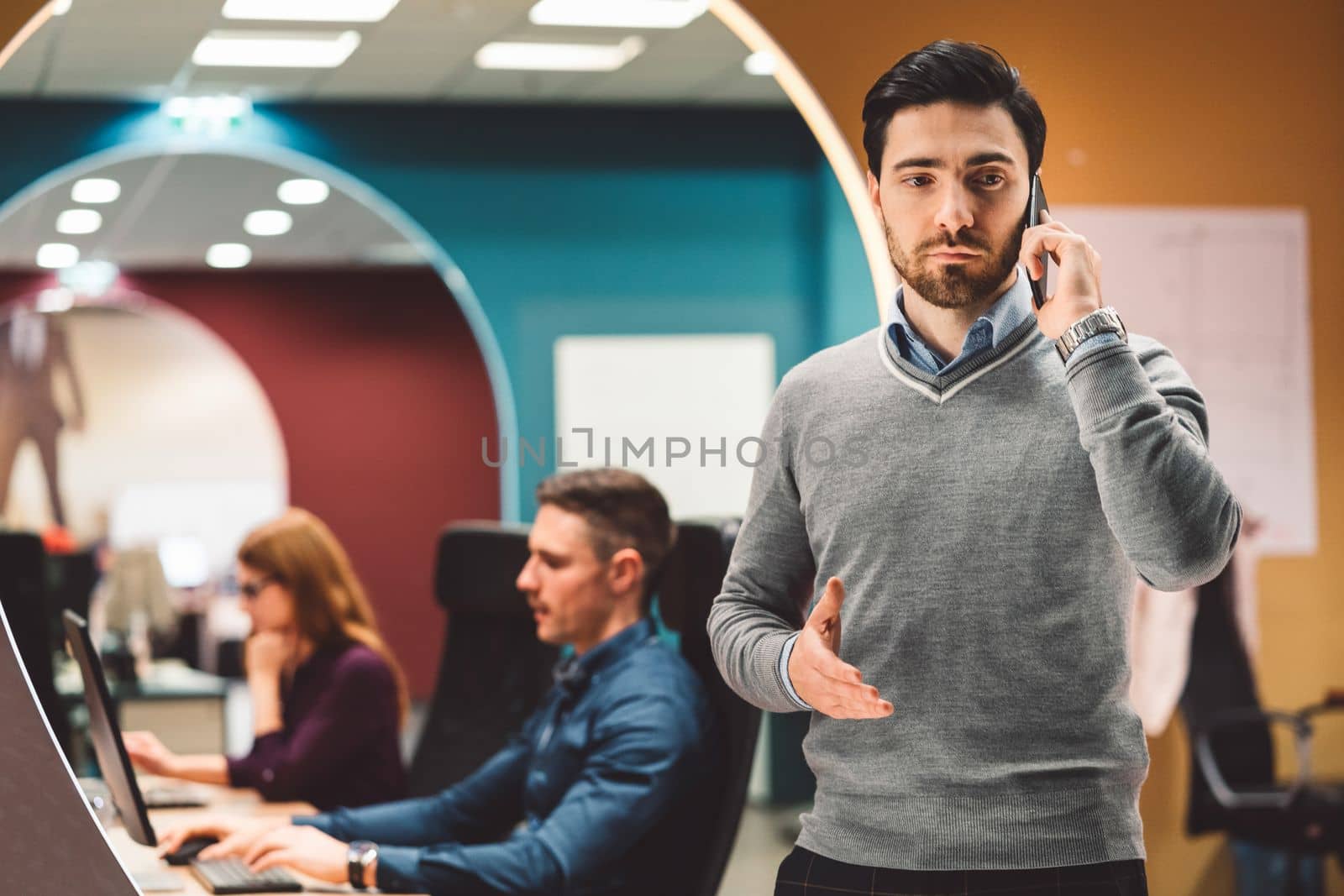 Young businessman having a business call, taking on the phone with a serious face expression by VisualProductions