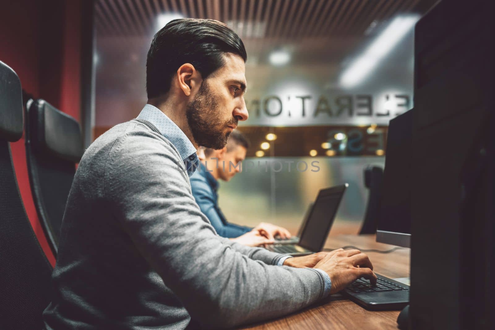 Side profile of a young tech man working on computer in the office by VisualProductions