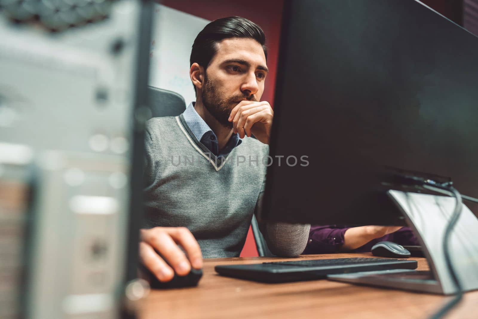 Young bearded business man sitting in the office working on computer by VisualProductions