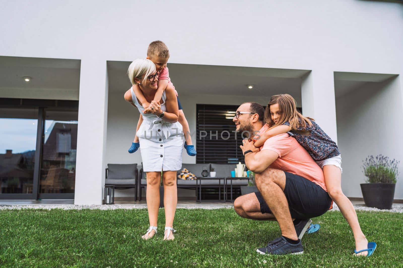Young family of for having fun spending time together playing outside the house on the grass by VisualProductions