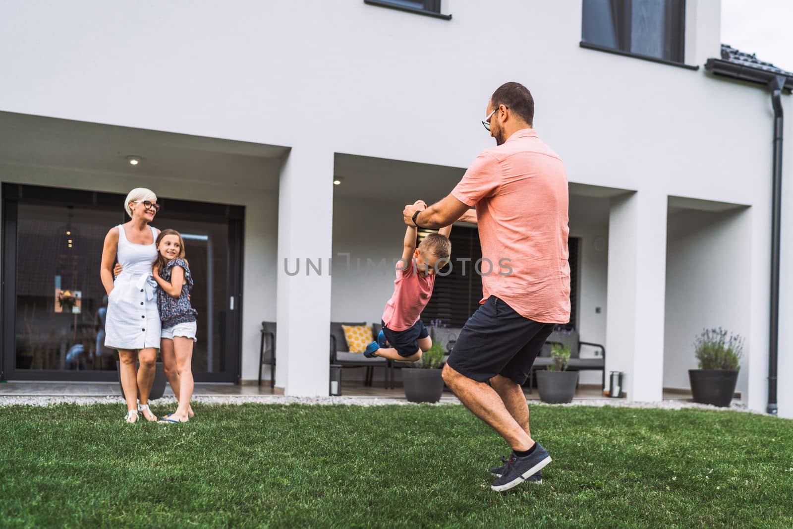 Young family spending time together on the weekends, playing games outside the house in the summer by VisualProductions