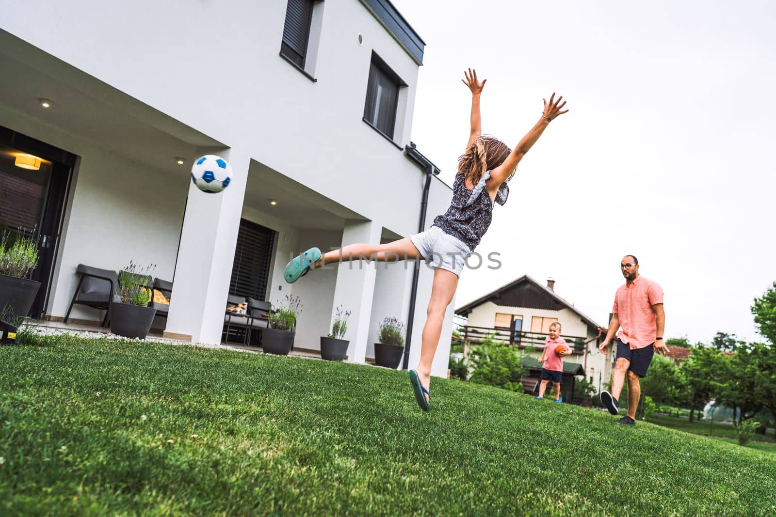 Happy caucasian family of four, mother father and children at home, outdoors playing on the grass, and indoors in the living room having fun as a family.