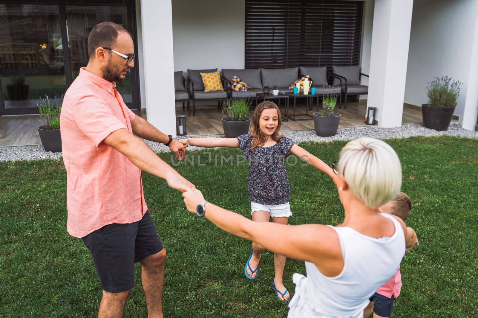 Happy caucasian family of four, mother father and children at home, outdoors playing on the grass, and indoors in the living room having fun as a family.