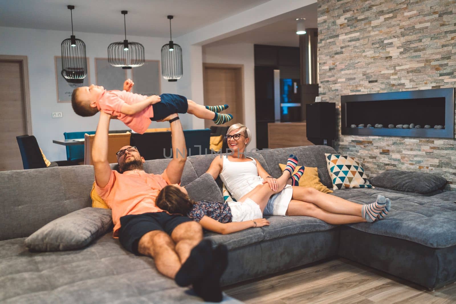 Happy caucasian family of four, mother father and children at home, outdoors playing on the grass, and indoors in the living room having fun as a family.