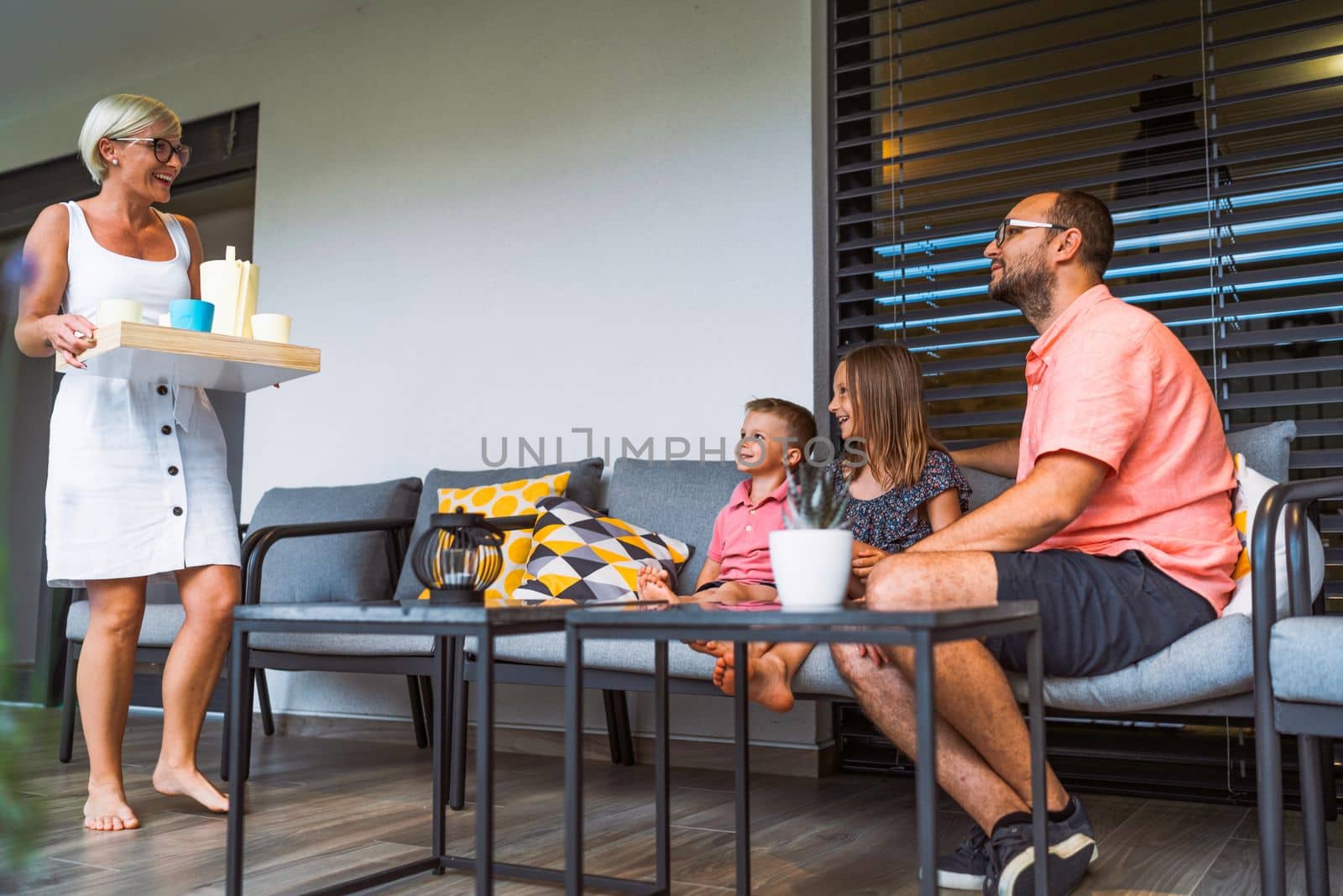 Mom holding a lemonade tray for the family sitting on the chairs outside waiting for refreshments by VisualProductions