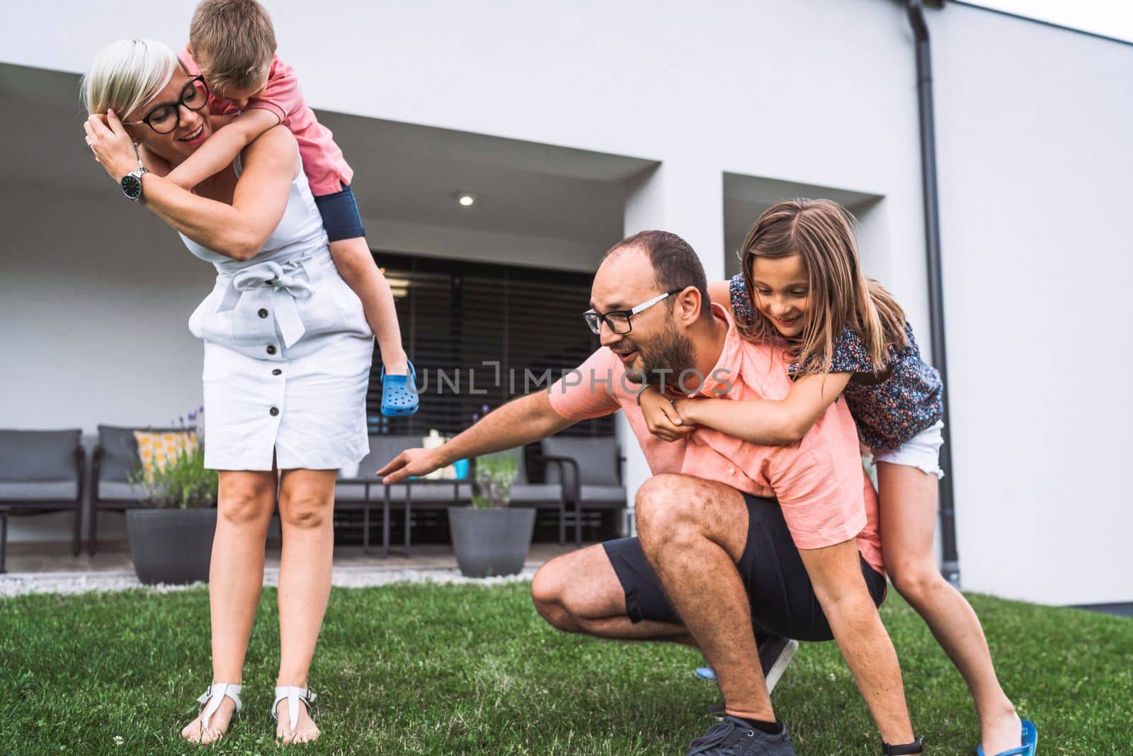 Loving caucasian family of four playing games outside the house on the grass by VisualProductions