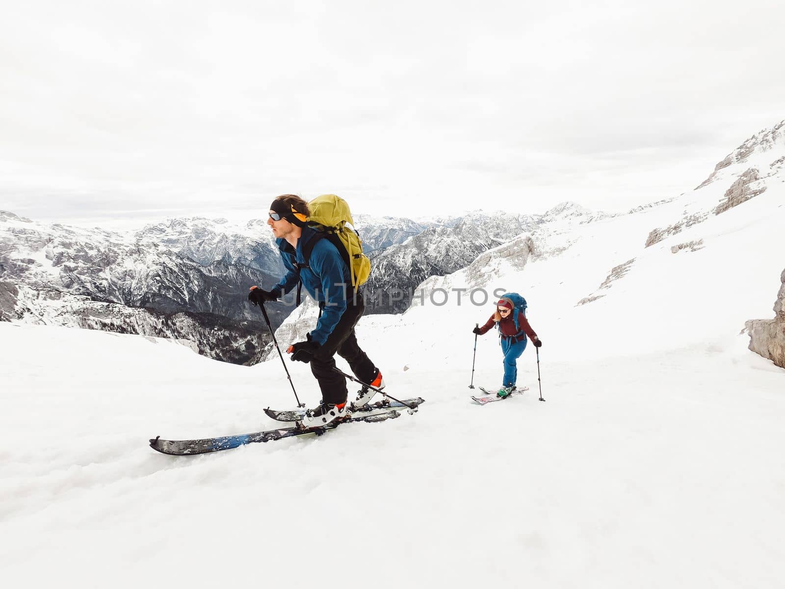 Adventurous couple ski touring high up in the snowy Alps on a beautiful winter day by VisualProductions