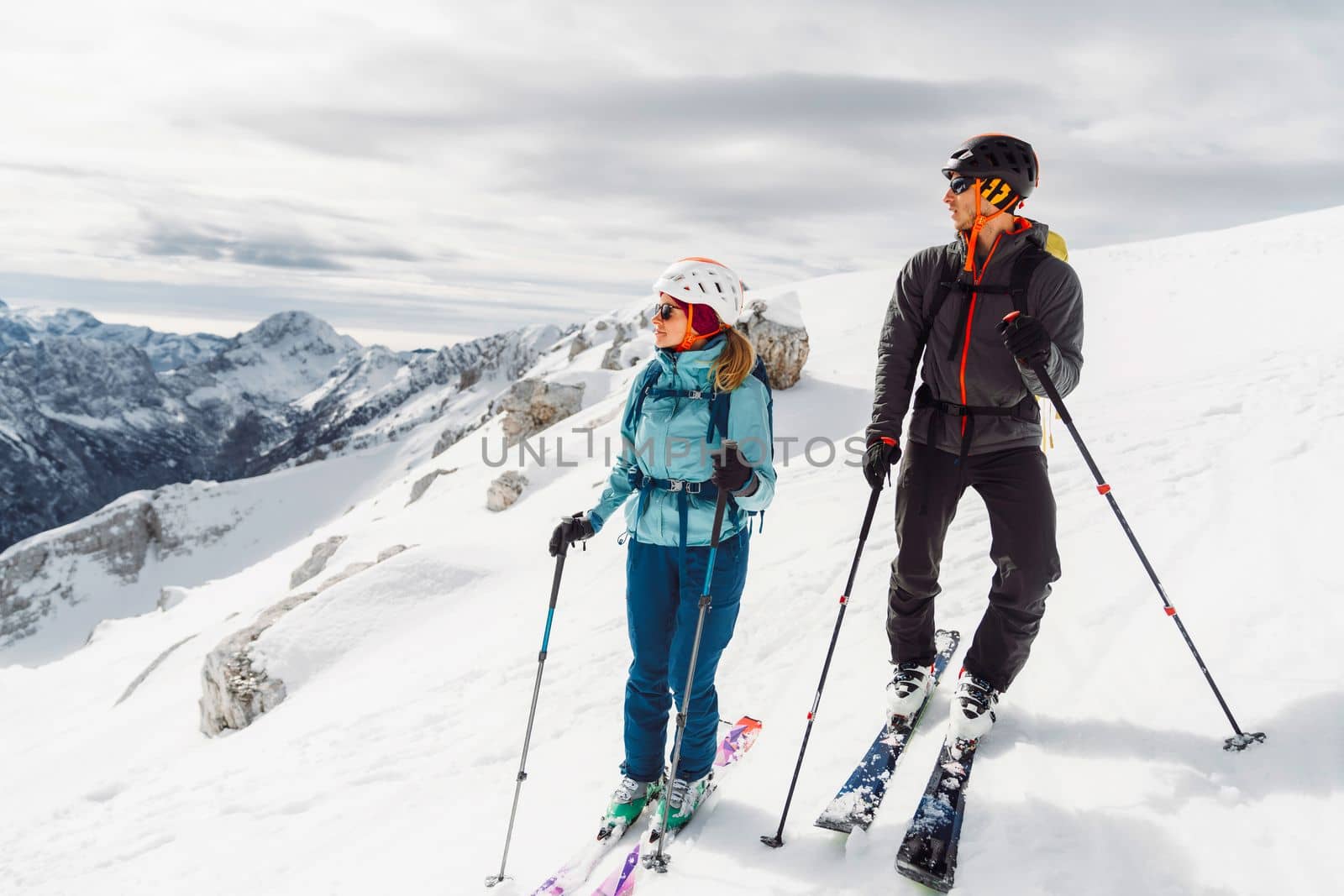 Woman ski tourer and man ski tourer looking at the views of the mountains from high up by VisualProductions