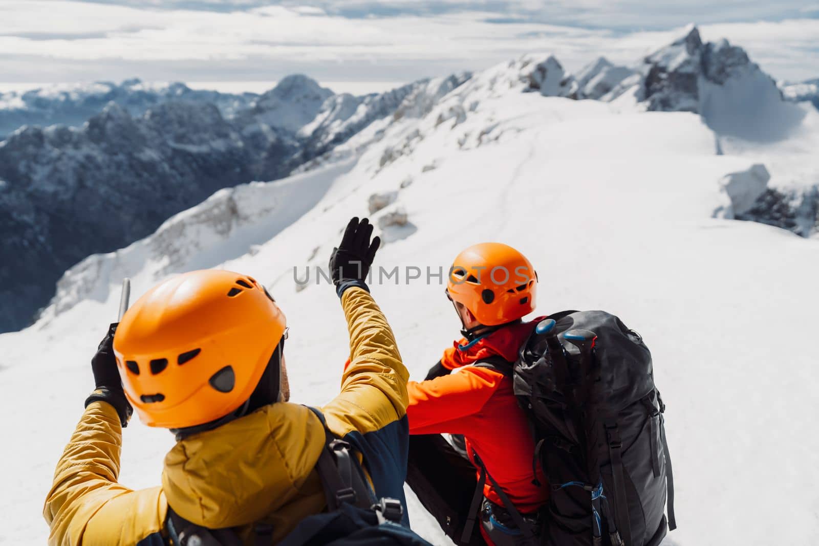 Over the head view, two mountaineers with helmets looking at the view of snowy Alps from high up by VisualProductions