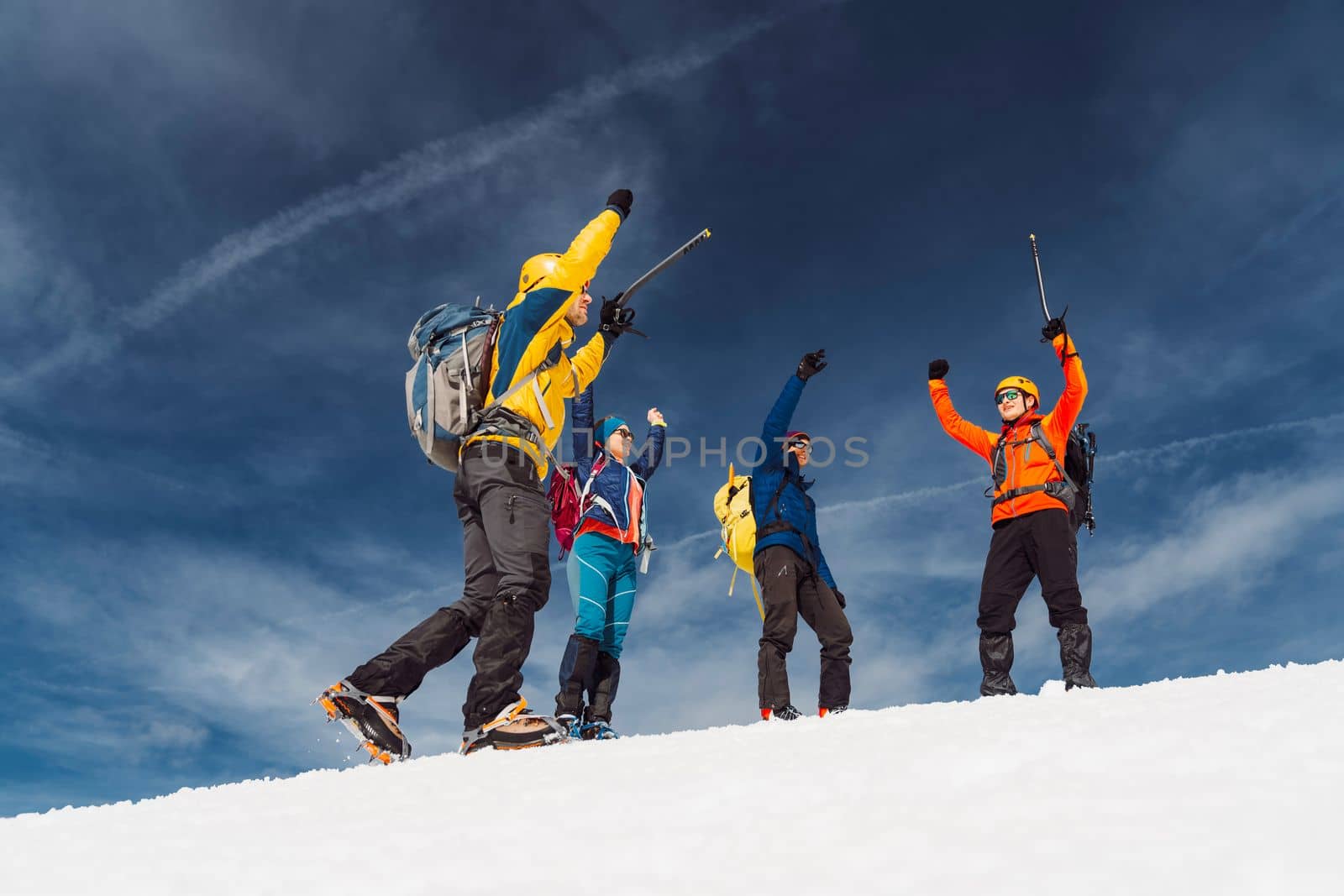 Group of happy hikers with their hands up in the air getting excited to reach the top of the mountain by VisualProductions
