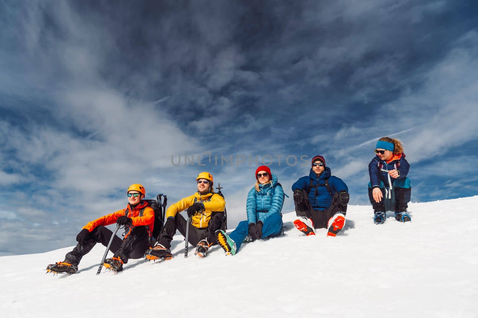 Group of five mountaineers sitting on the sun, high up in the snowy Alps by VisualProductions