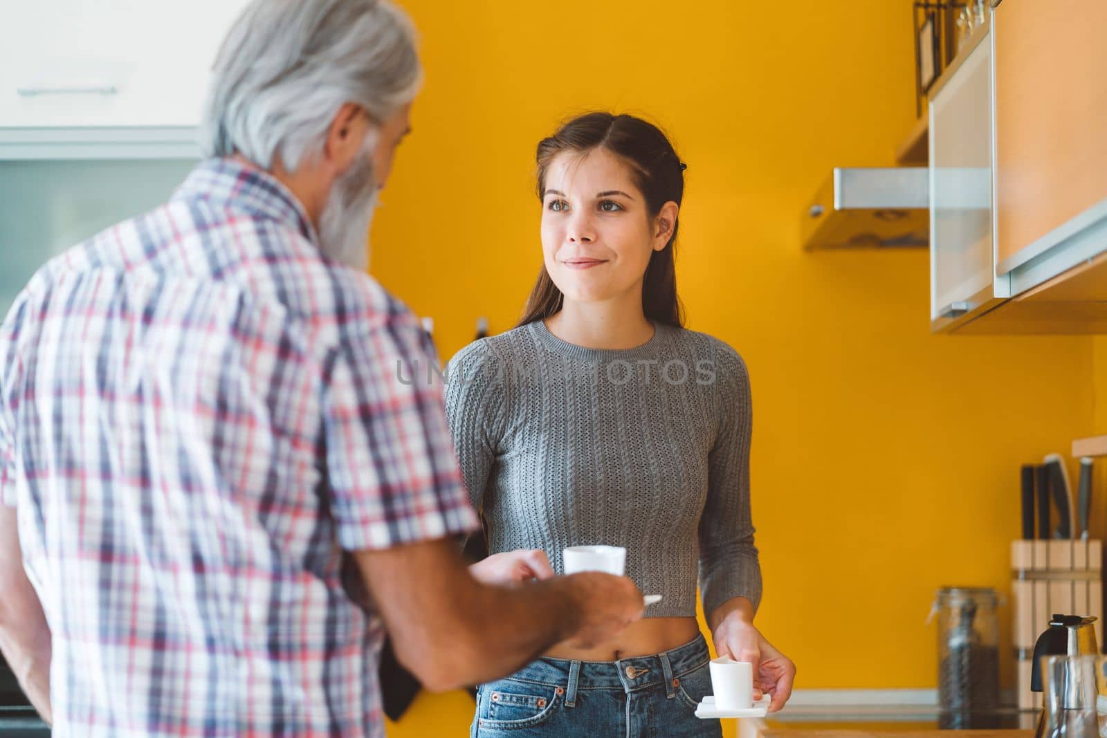 Young caucasian woman taking care of her grandfather, senior man with beard and grey hair. Granddaughter visiting her grandfather, spending quality time together.
