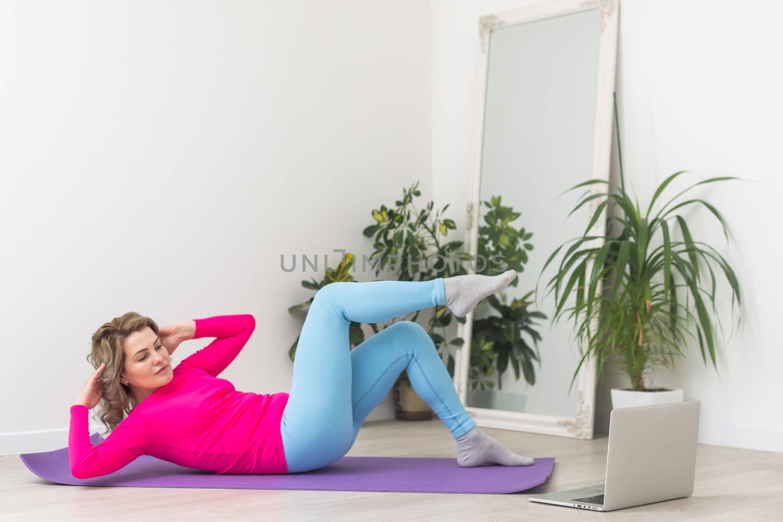 Attractive young woman doing yoga stretching yoga online at home. Self-isolation is beneficial, entertainment and education on the Internet. Healthy lifestyle concept by Andelov13
