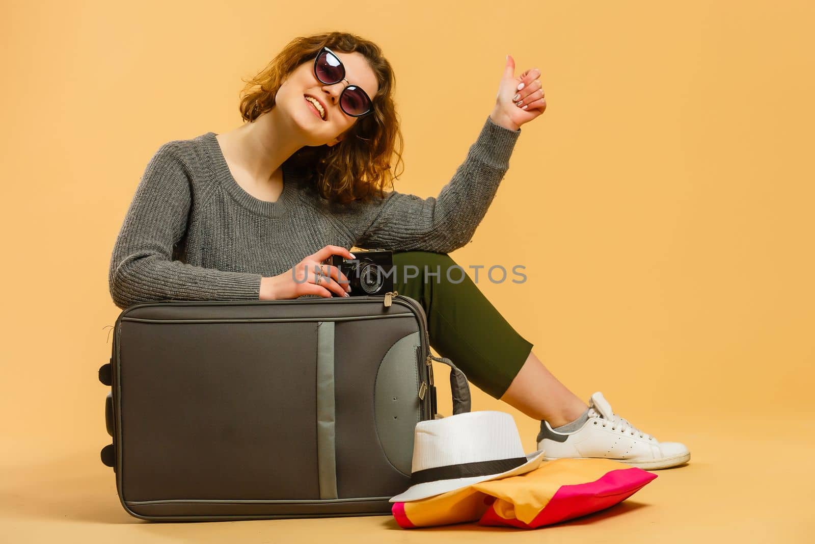 Ready for vacation. Traveling concept. Young excited woman sitting luggage valise. Isolated