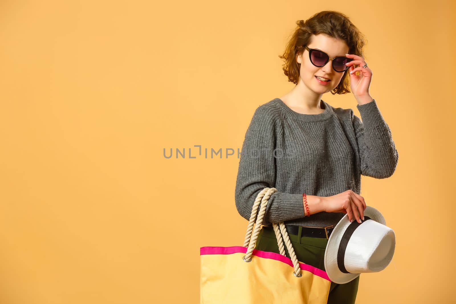 Traveler tourist woman in summer casual clothes, hat with suitcase isolated on yellow orange background. Female passenger traveling abroad to travel on weekends getaway. Air flight journey concept by Andelov13