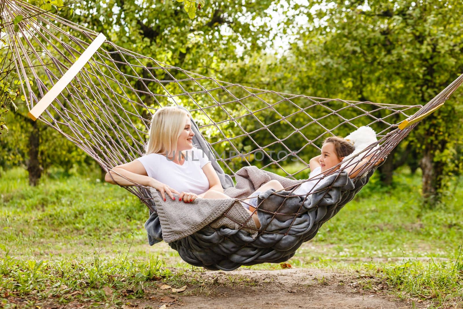 loving family spends time together in summer time enjoy the little things. slow life. mom and little daughter relax in a hammock in the summer in the garden by Andelov13