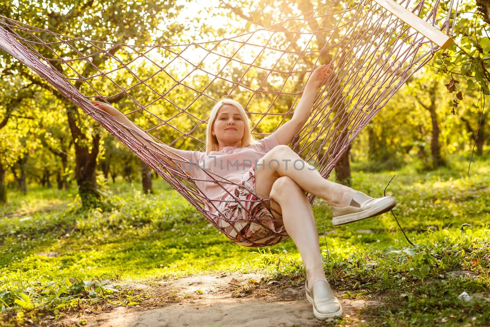 Smiling blonde woman relaxing on the hammock in garden, leisure time and summer holiday concept by Andelov13