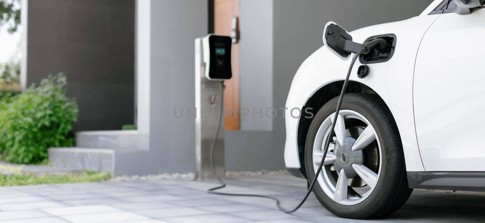 Progressive concept of EV car and home charging station powered by sustainable and clean energy with zero CO2 emission for green environmental. Charging point at residential area for electric vehicle.