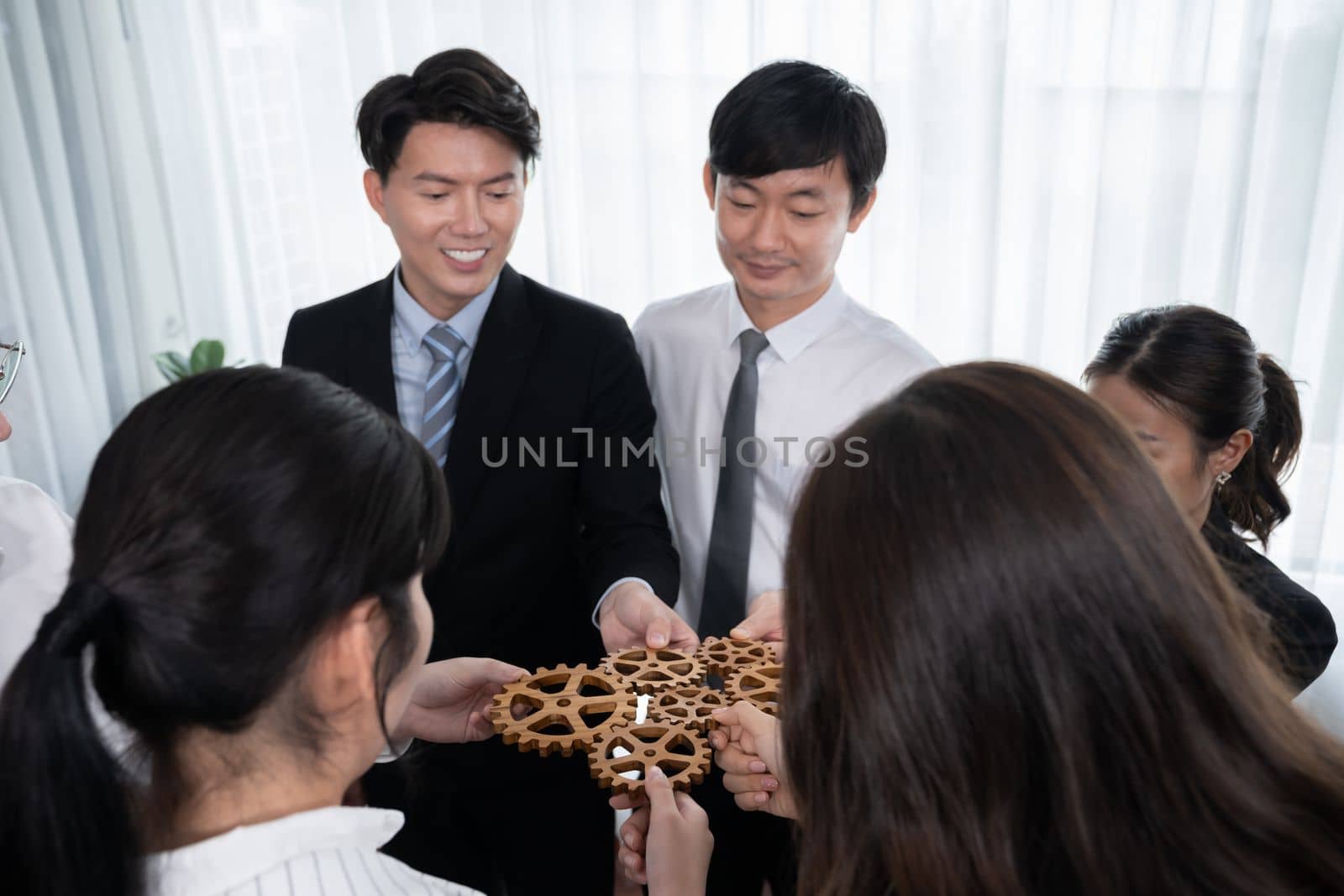 Group of people making chain of gears into collective form for harmony symbol. by biancoblue