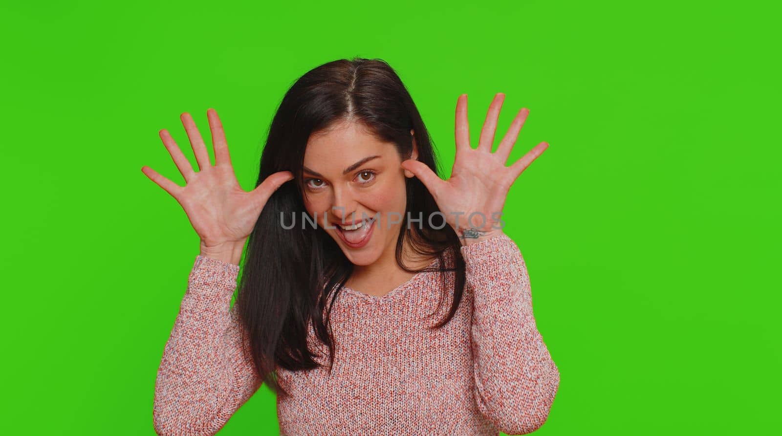 Funny joyful sincere woman 30 years old dancing, making playful silly facial expressions and grimacing, fooling around showing tongue. Young lovely pretty girl isolated alone on chroma key background
