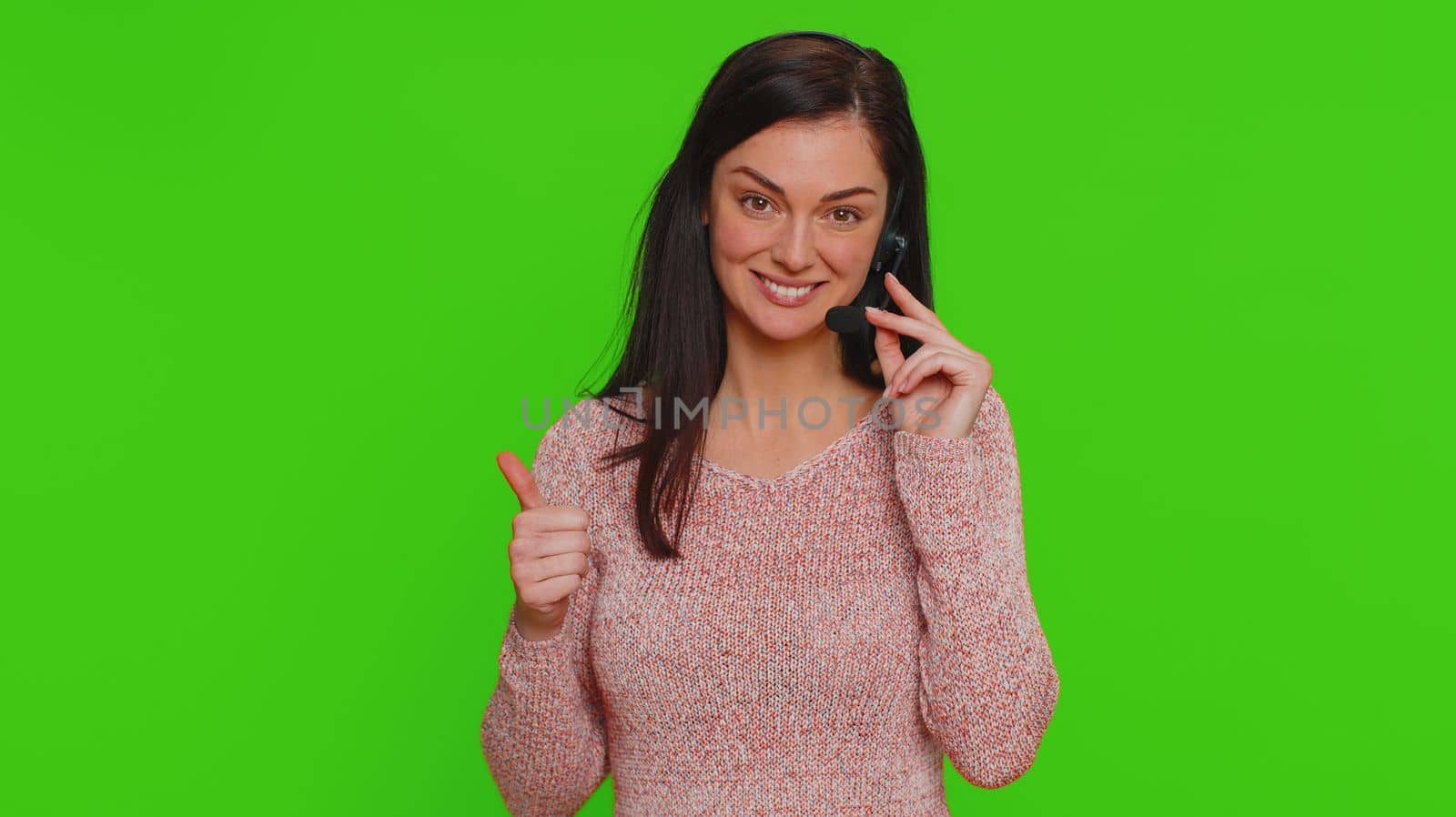 Smiling woman wearing headset, freelance worker, call center or support service operator helpline, having talk with client or colleague communication support. Young girl on green chroma key background