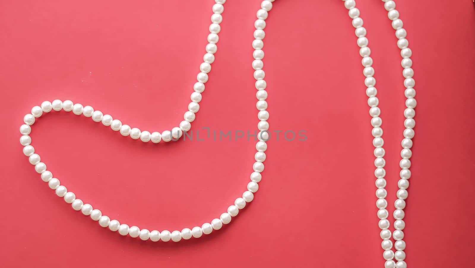 Pearl jewellery necklace on coral background.