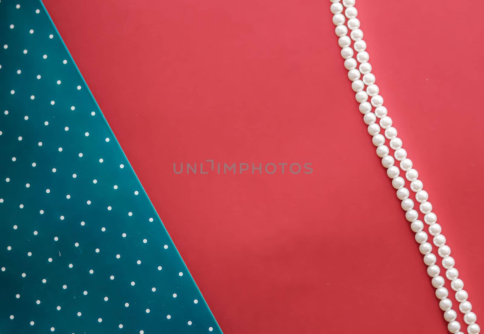 Pearl jewellery necklace and abstract blue polka dot background on coral backdrop by Anneleven