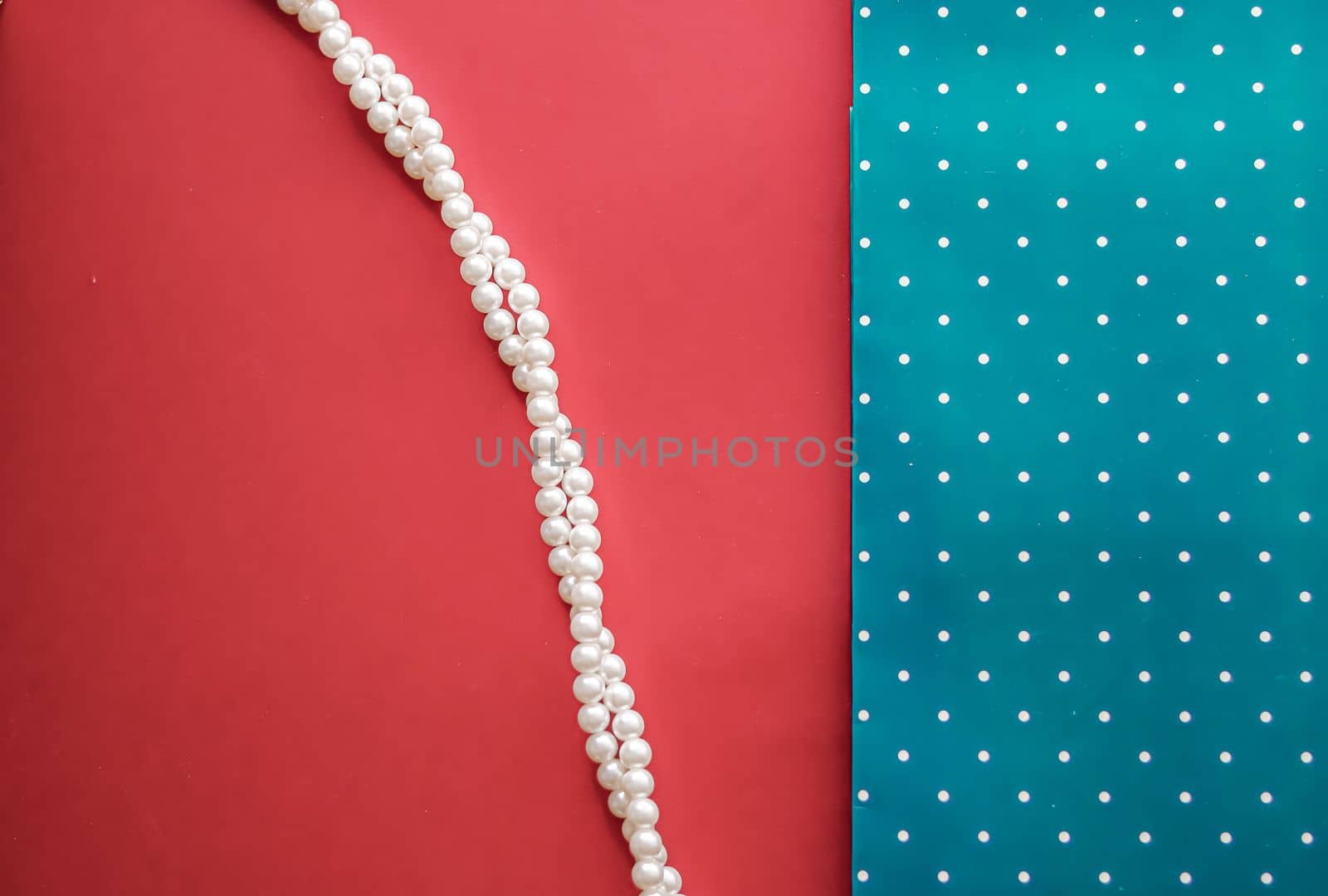 Pearl jewellery necklace and abstract blue polka dot background on coral backdrop.