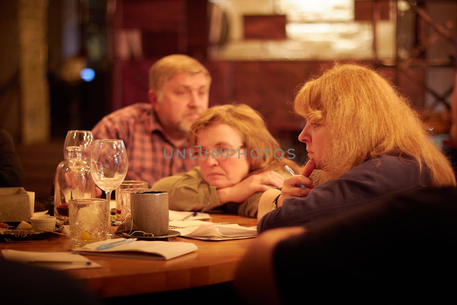 Kirov, Russia - September 13, 2022: People at table in small cafe or restaurant during intellectual game. Hungry group discussing the menu in the restaurant and waiting for waiter. Partial focus