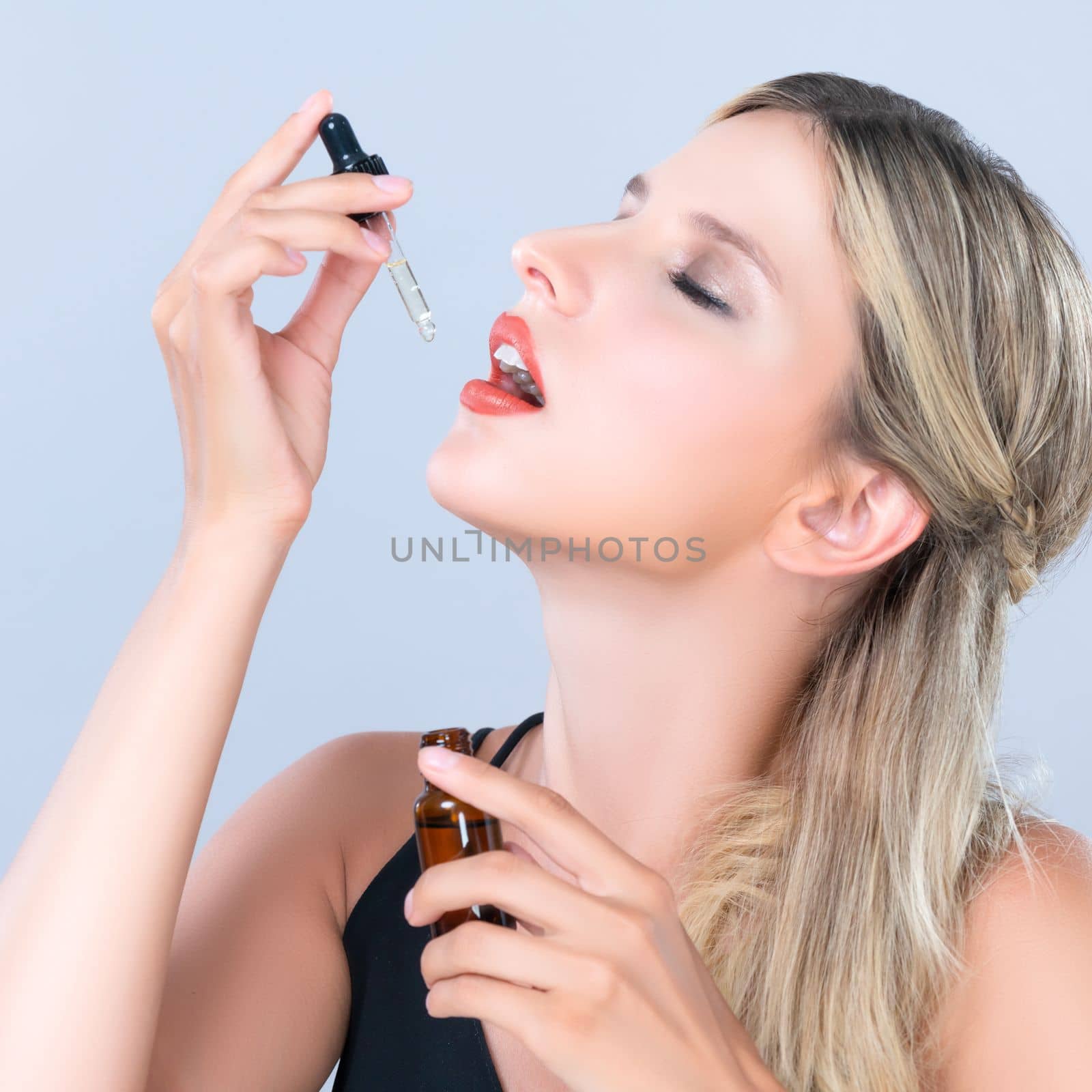 Alluring portrait of beautiful woman applying extracted cannabis oil bottle for skincare product. CBD oil dropper pipette for cosmetology treatment and beauty concept.