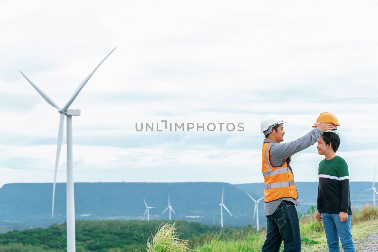 Progressive engineer with his son in the wind farm atop of the mountain. by biancoblue