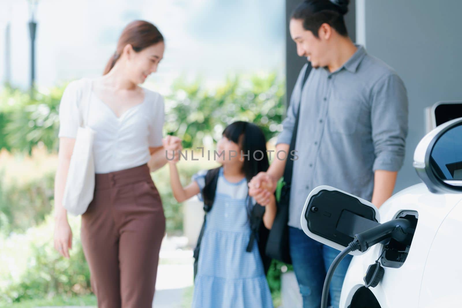 Focus home charging station for EV car, blur progressive family in background. by biancoblue