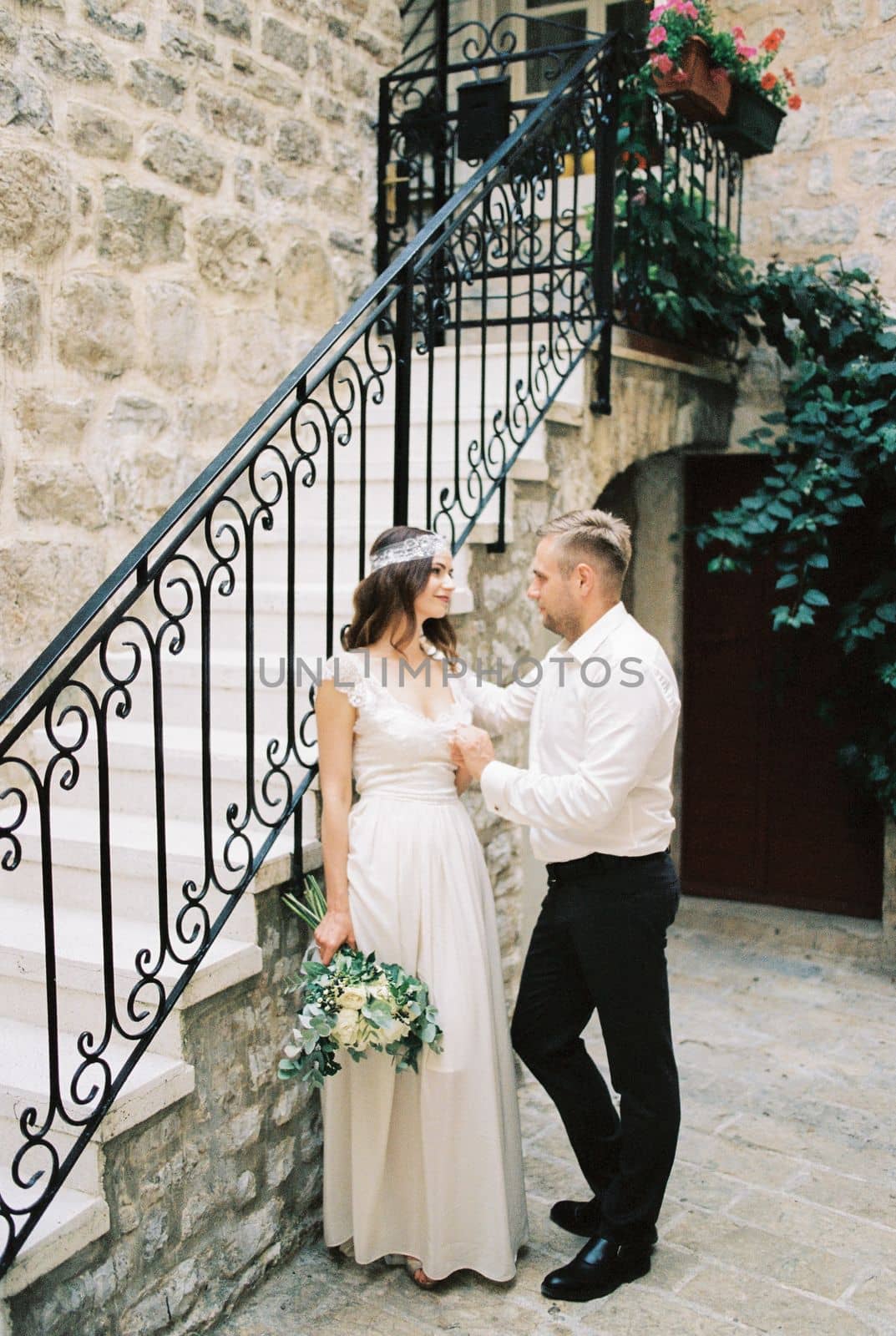 Bride and groom are standing near the stairs of an old stone house. High quality photo