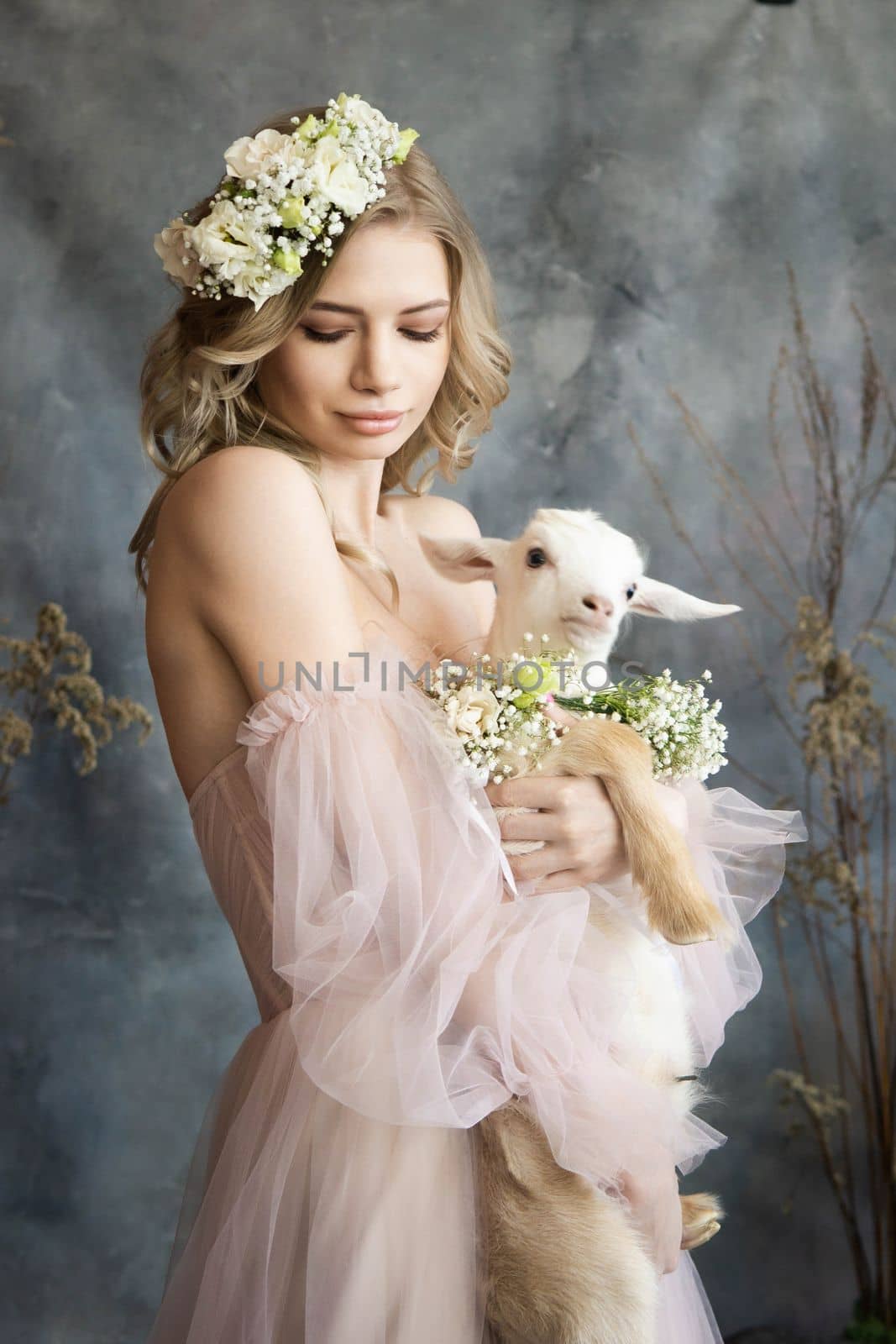 A young blonde woman in an airy pink dress with a white kid. Spring portrait of a woman