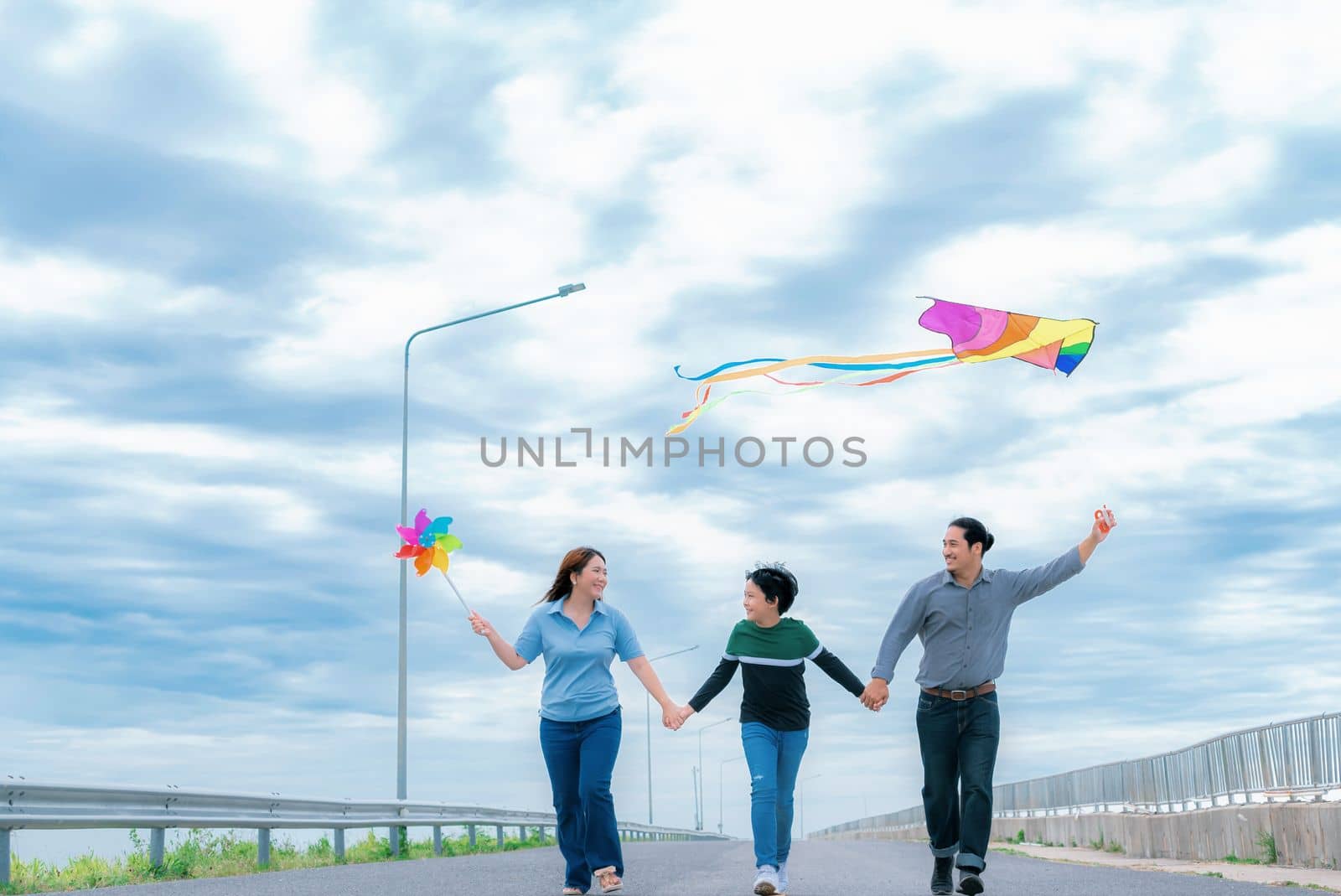 Progressive happy family vacation concept with outdoor flying kite on the road by biancoblue