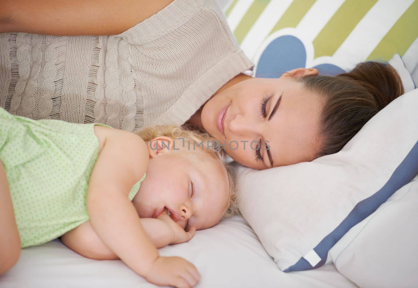 Shes always close to her baby. A young mother lying next to her sleeping baby on the bed. by YuriArcurs