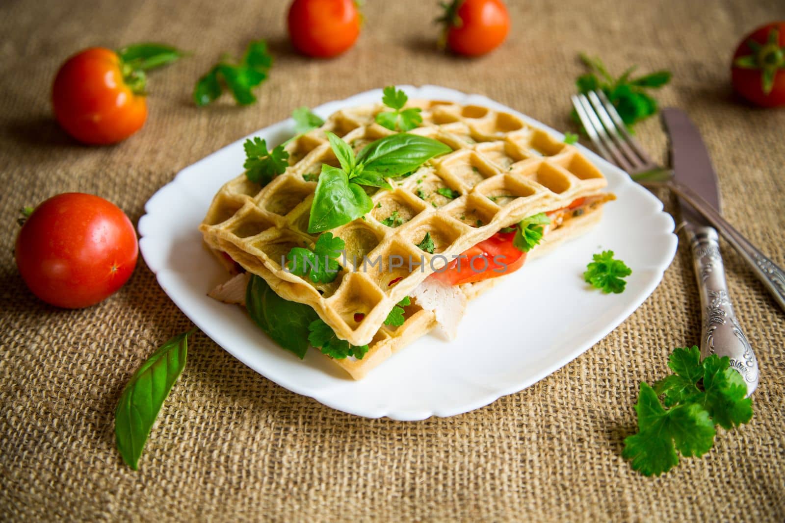Sandwich of two egg omelettes with bacon and tomatoes inside, waffle shaped.