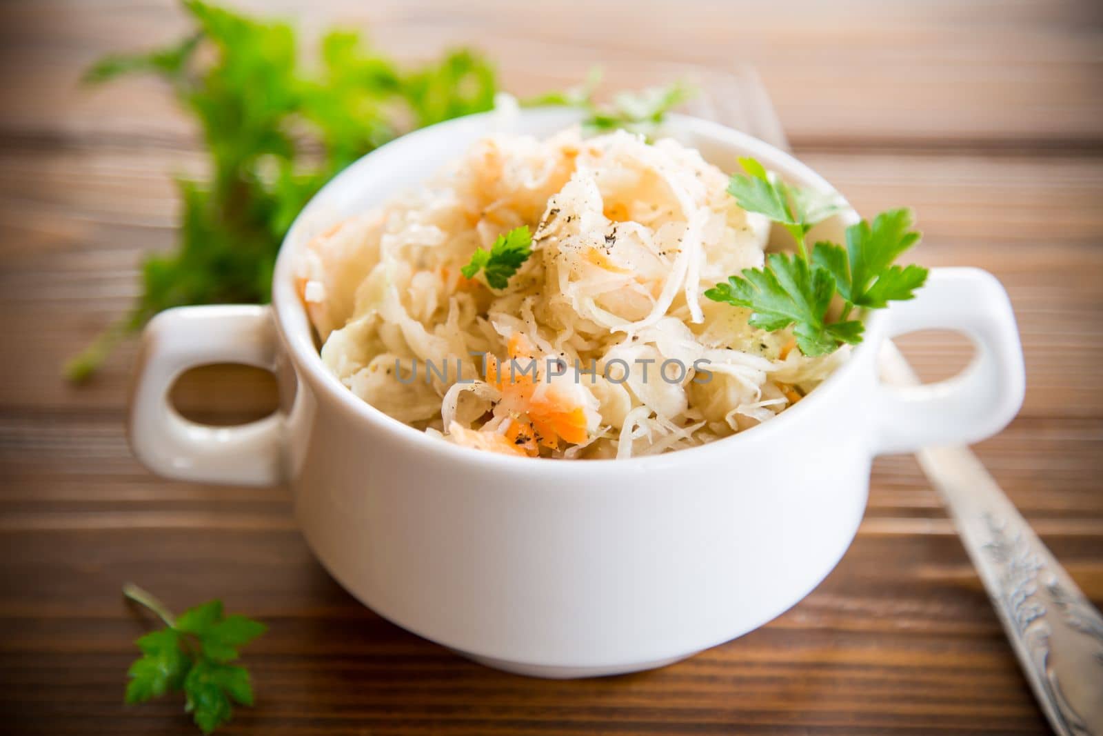 sauerkraut with carrots and spices in a bowl on a wooden table.