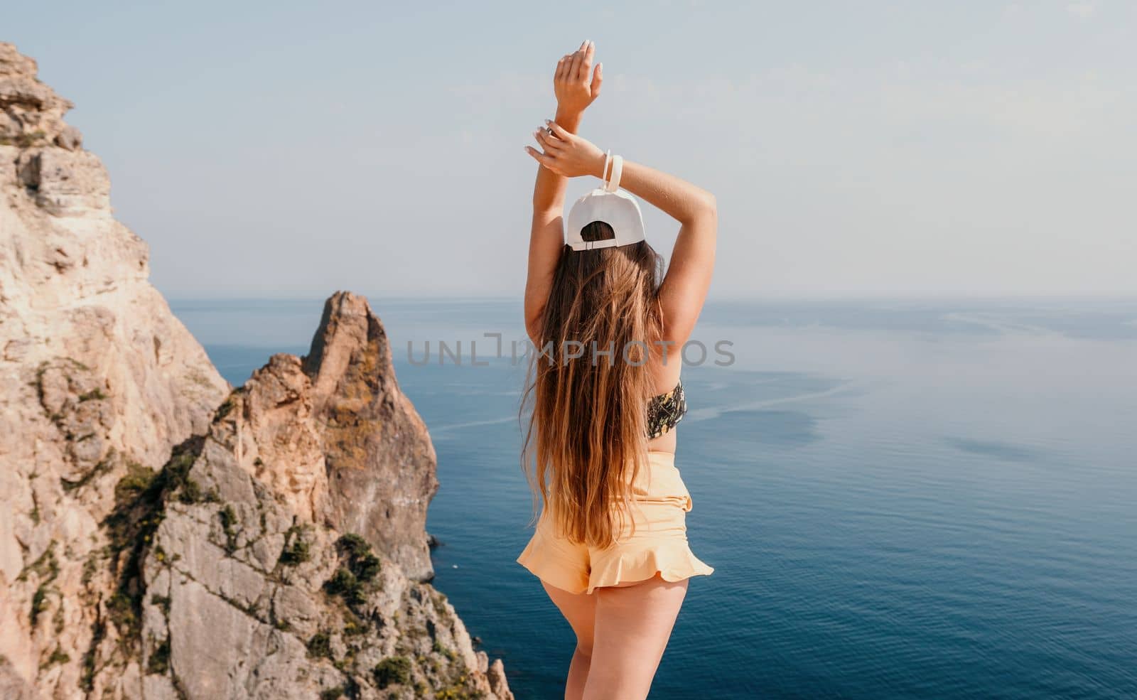 Woman travel sea. Happy tourist enjoy taking picture outdoors for memories. Woman traveler looks at the edge of the cliff on the sea bay of mountains, sharing travel adventure journey by panophotograph