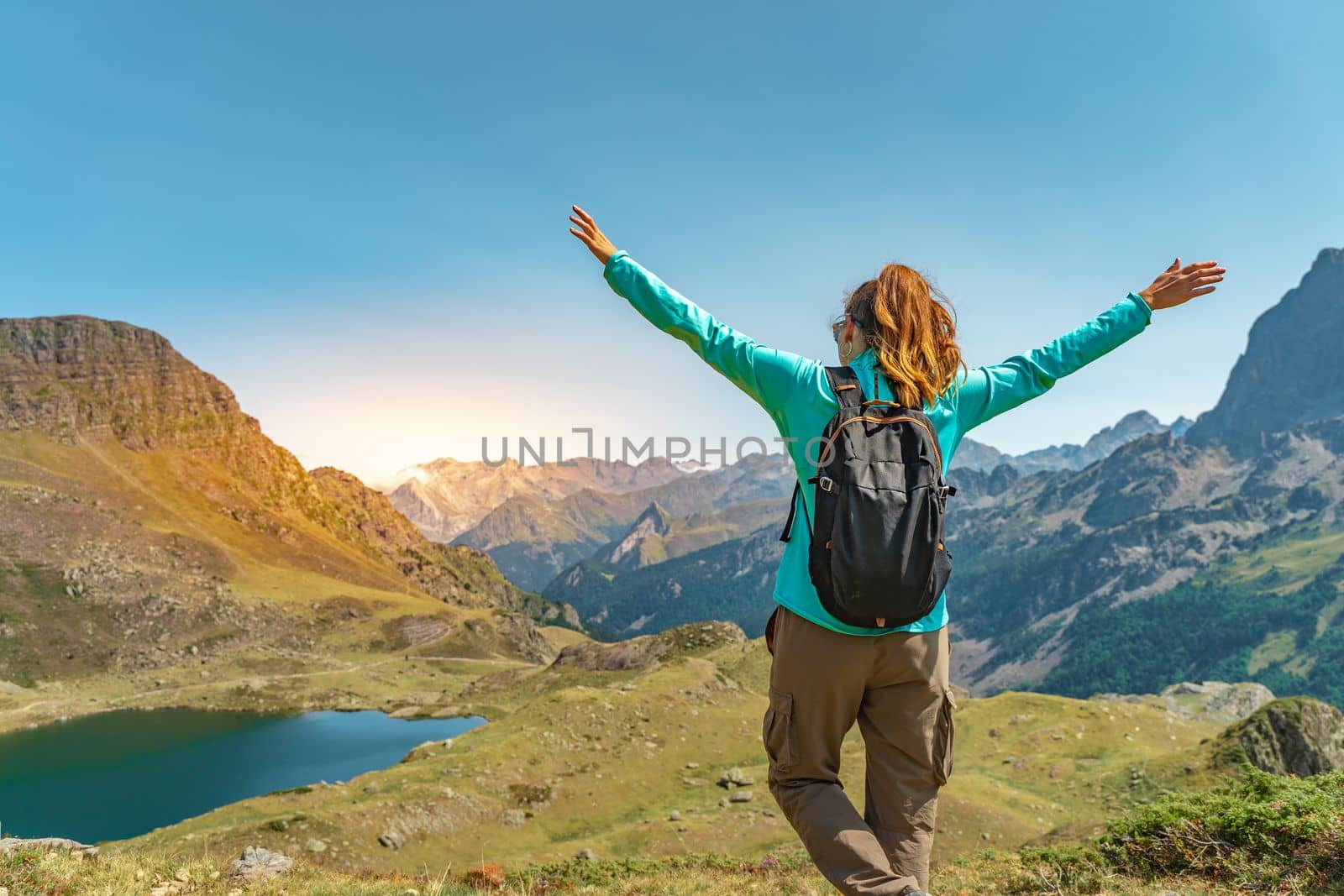 Attractive young woman with open arms enjoying life in the middle of a mountain with a lake in a beautiful landscape. High quality photo