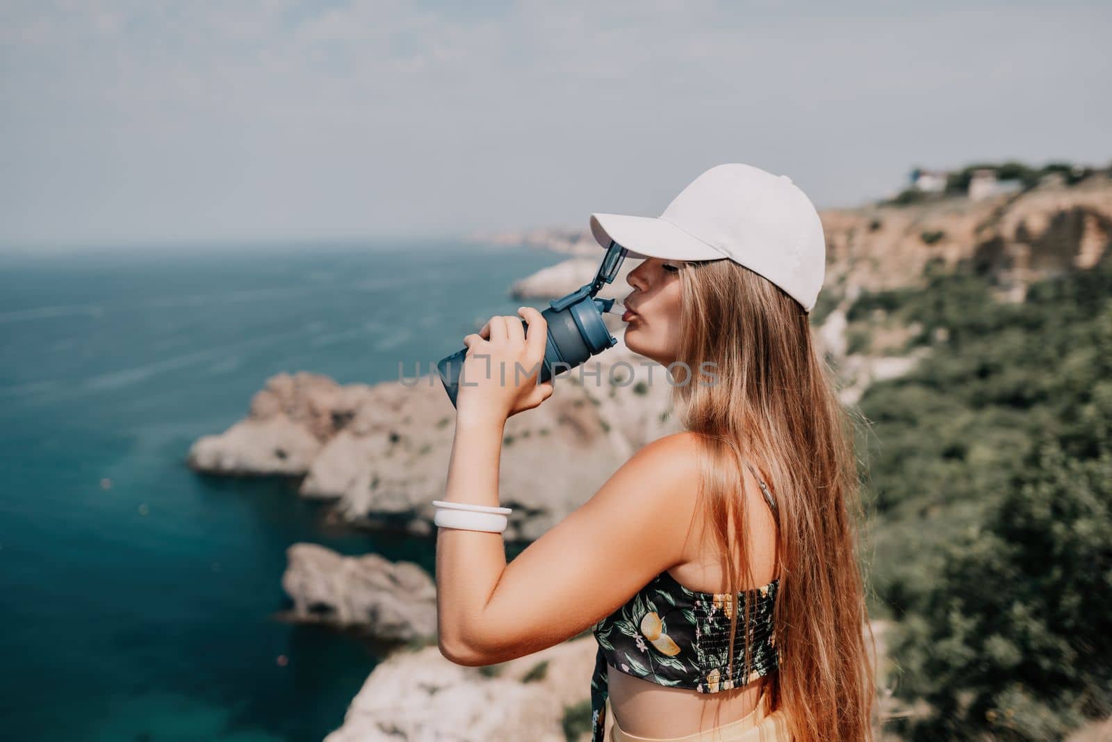 Woman travel sea. Happy tourist taking picture outdoors for memories. Woman traveler looks at the edge of the cliff on the sea bay of mountains, sharing travel adventure journey.