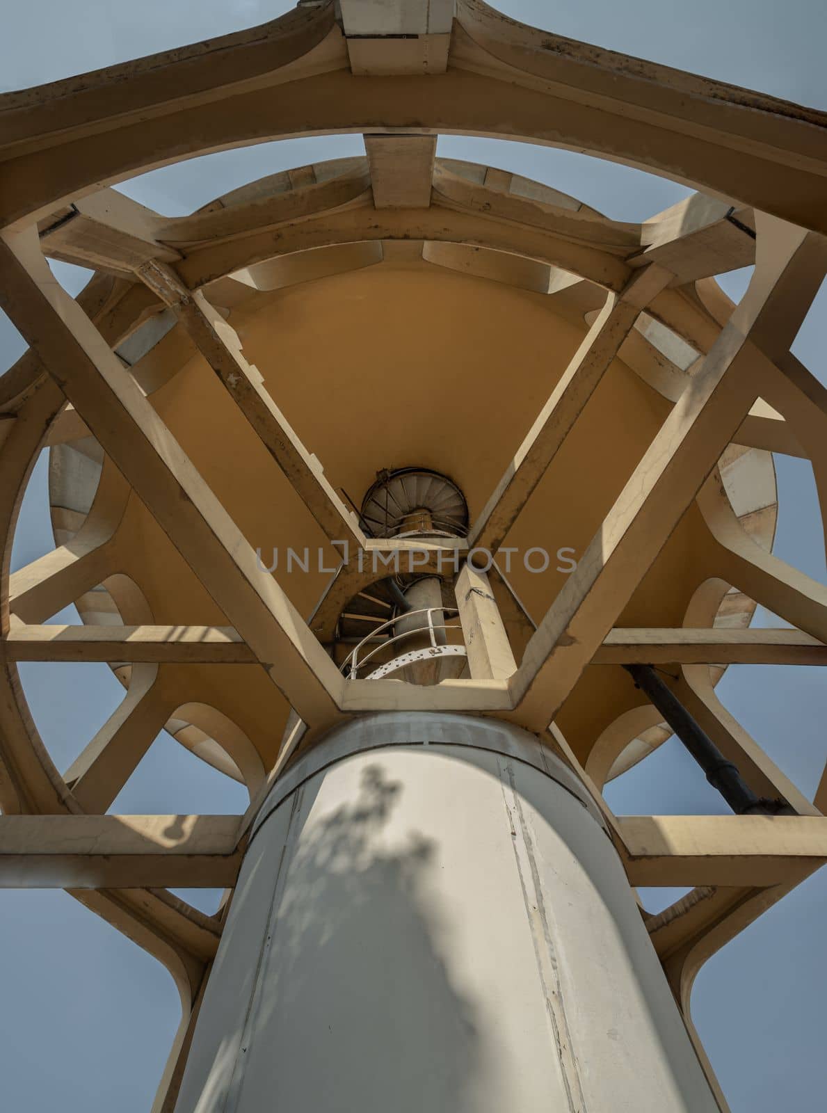 Bangkok, Thailand - 09 Feb, 2023 - A bottom-up view of columnar structures old water tower made of cement and metal spiral staircase. Large water tank in the water supply system. Selective focus.